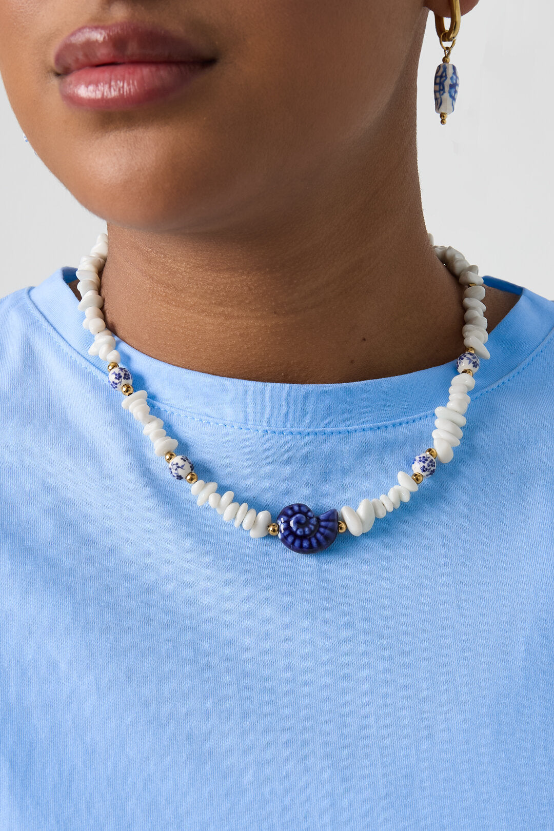 Ketting met stenen kralen, witte kralen met blauwe bloemetjes en statement schelp